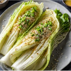 2 wedges of napa cabbage that is roasted and topped with dijon mustard sauce, sesame seeds, and scallions