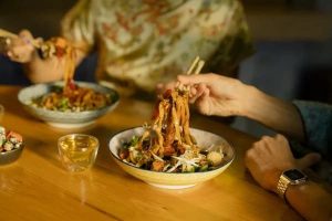 asian style noodles on a tablet being picked up with chopsticks