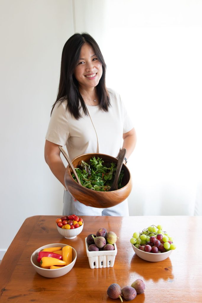 Asian woman with bowl of salad and ingredients on table