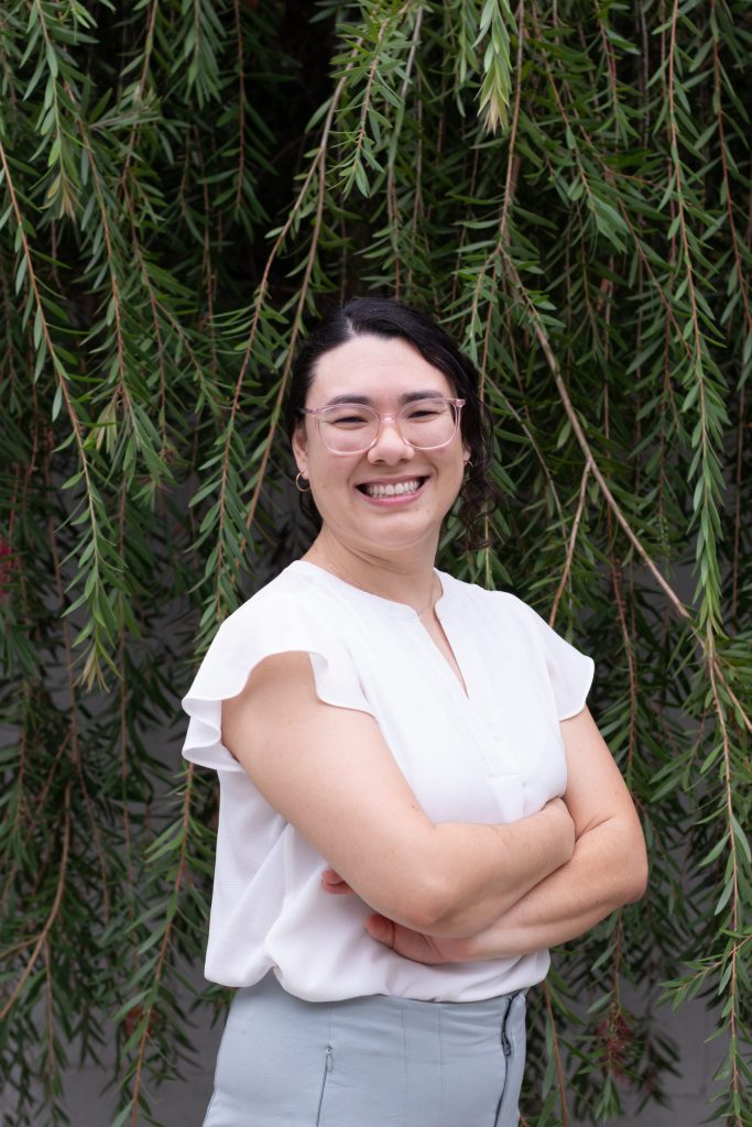 Professional headshot of smiling woman in glasses and white blouse