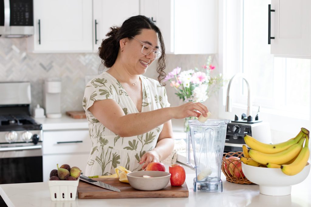 Smiling woman in modern kitchen preparing a smoothie