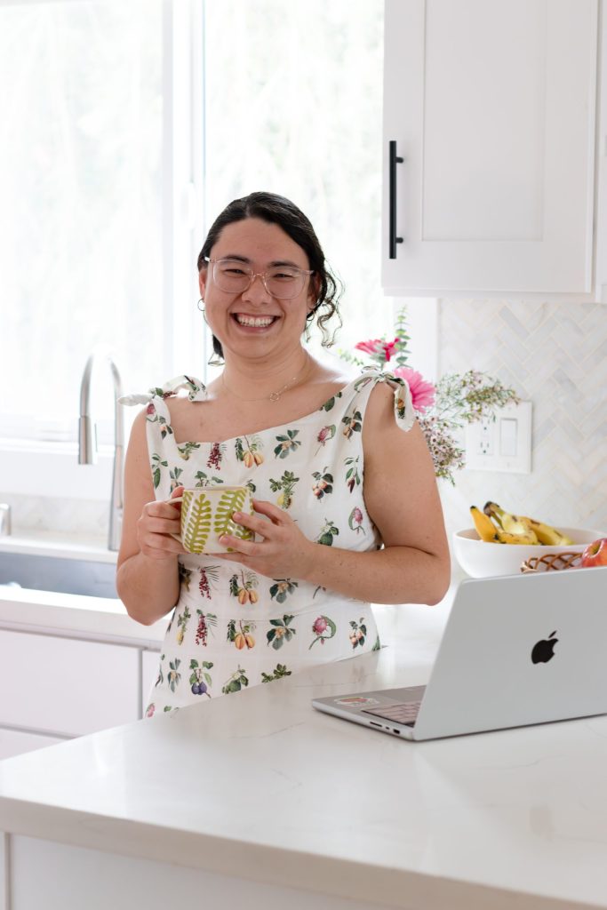 Mixed Asian and white professional woman in kitchen with a laptop