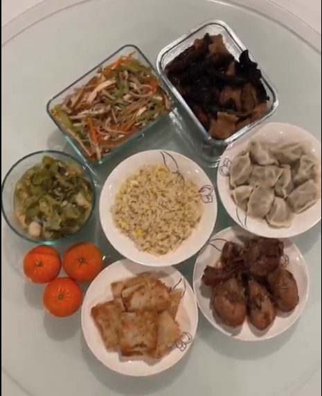 image of my lunar new year feast this year - a dish of mustard greens that were boiled and sauteed, a bowl of fried rice, a plate with nian gao, a plate of chicken legs, a plate of dumplings, a bowl with bean curd mixed with celebry and carrots, and a braised pork dish.