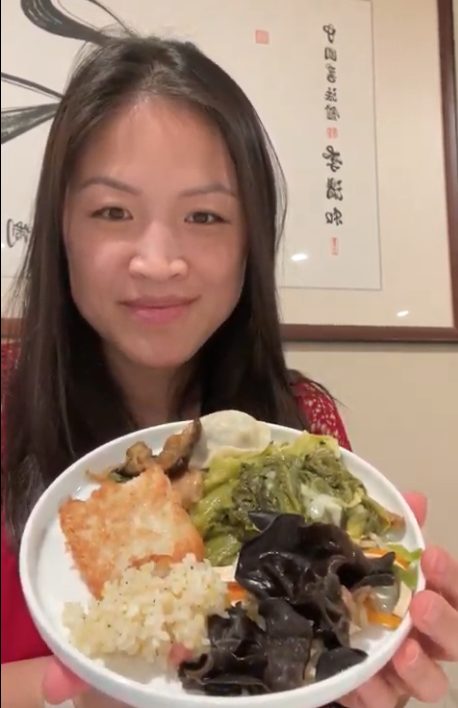 an image of Edith Yang, registered dietitian, holding a plate of the foods eaten at lunar new year. There is black fungus mushroom, radish cake, fried rice, mustard greens, dumplings, and the vegetarian bean curd dish.